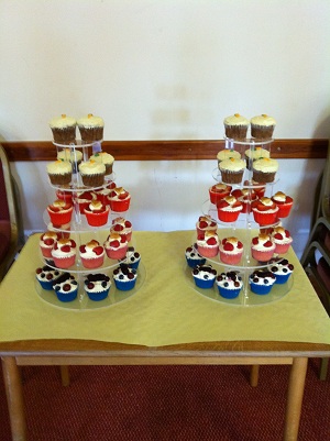 4 tier display stand with variety of large and small cupcakes plus a top tier cake