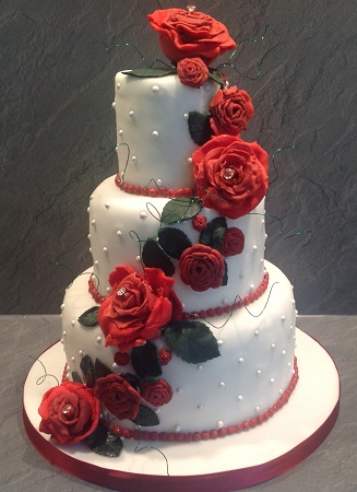 3 tier traditional wedding cake with red flowers