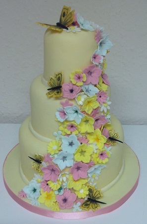 3 tier cake with yellow and pink flowers and butterflies